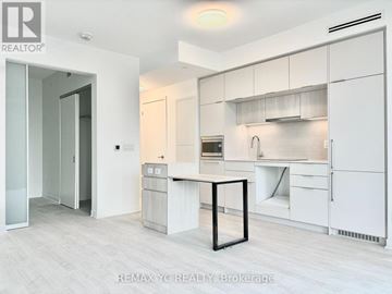 Toronto (Oakwood Village) condo for rent - A white kitchen with a table and a fridge.