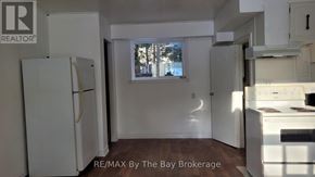Wasaga Beach multi-family for rent - A kitchen with white appliances and a window.