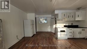 Wasaga Beach multi-family for rent - A kitchen with white cabinets and a black countertop.