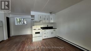 Wasaga Beach multi-family for rent - A kitchen with white cabinets and a wooden floor.