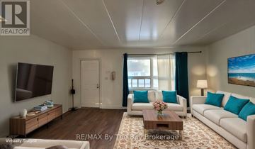 Wasaga Beach multi-family for rent - A living room with a white couch, a wooden coffee table, and a painting on the wall.