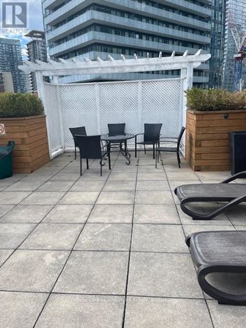 Toronto (Mount Pleasant West) condo for rent - A patio with a white pergola and black chairs.