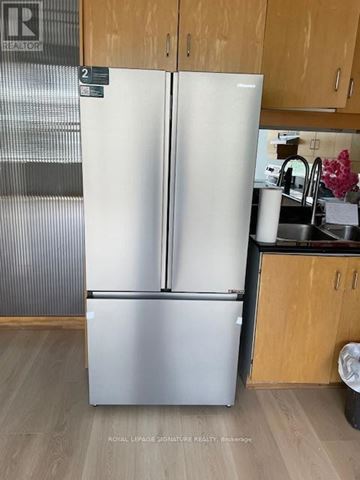 Toronto (Mount Pleasant West) condo for rent - A white fridge in a kitchen with wooden cabinets.