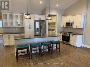 Southwest Middlesex (Wardsville) fourplex for rent - A kitchen with white cabinets and a bar area with stools.