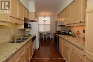 Oakville (Ro River Oaks) condo for rent - A kitchen with wooden cabinets and granite countertops.