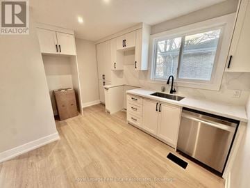 Brantford multi-family for rent - A kitchen with white cabinets and a stainless steel dishwasher.