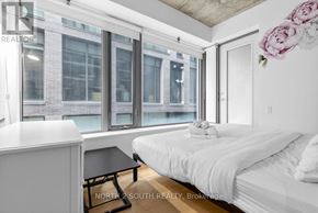 Toronto (Waterfront Communities) condo for rent - A bedroom with a bed, nightstand, and window overlooking a city street.