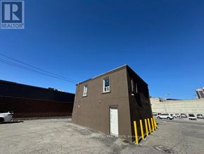 Brampton (Downtown Brampton) apartment for rent - A brown building with a white door and windows is surrounded by a parking lot.
