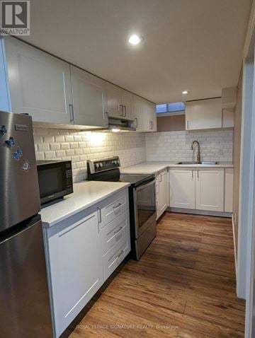 Milton (Be Beaty) apartment for rent - A kitchen with white cabinets and a wooden floor.