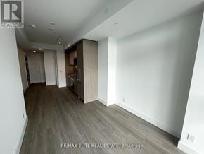 Toronto (Bayview Village) condo for rent - A spacious room with wood flooring and white walls.