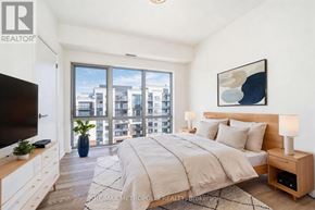 Clarington (Bowmanville) condo for rent - A bedroom with a large bed, a flat screen TV, and a view of the city.