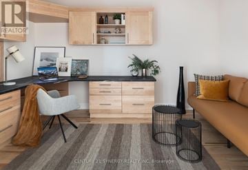 Smiths Falls condo for rent - A living room with a brown couch, a desk with a chair, and a rug on the floor.