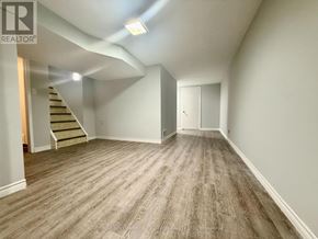 Ajax (South East) apartment for rent - A spacious room with wooden flooring and a staircase leading to another level.