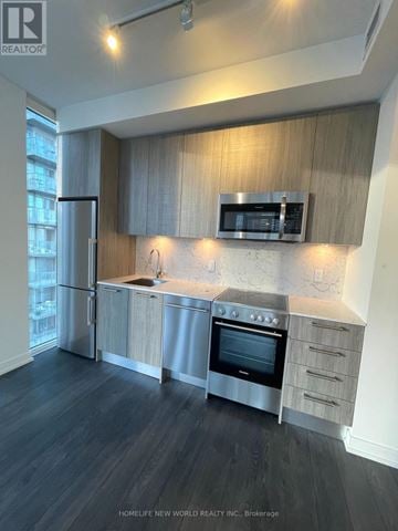 Toronto (Church-Yonge Corridor) condo for rent - A modern kitchen with dark wood floors and stainless steel appliances.