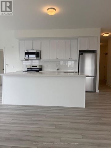 Clarington (Bowmanville) condo for rent - A modern kitchen with white cabinets and a large island.