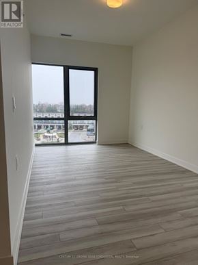 Clarington (Bowmanville) condo for rent - A room with a wooden floor and a large window.
