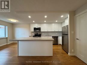 St. Catharines (Lakeport) condo for rent - A kitchen with white cabinets and a wooden floor.