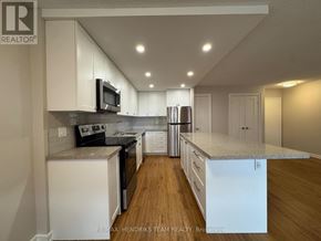 St. Catharines (Lakeport) condo for rent - A kitchen with white cabinets and a wooden floor.