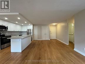 St. Catharines (Lakeport) condo for rent - A kitchen with white cabinets and a wooden floor.