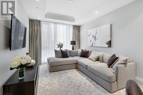 Toronto (Annex) condo for rent - A modern living room with a grey sofa and a large abstract painting on the wall.