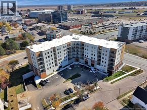 Moncton apartment for rent - A large white apartment building with a parking lot in front.