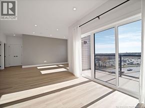 Moncton apartment for rent - A spacious room with a view of a parking lot and trees outside.