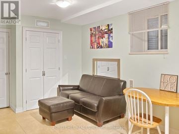 Toronto (Little Portugal) multi-family for rent - A living room with a brown leather couch and a white chair.