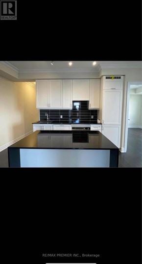 Vaughan (Concord) condo for rent - A kitchen with white cabinets and a black countertop.
