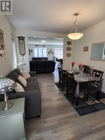 Milton (Cb Cobban) apartment for rent - A well-lit living room with a grey sofa and a dining table set for six.