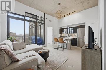 Ottawa condo for rent - A modern living room with a grey sofa and a glass door leading to a balcony.