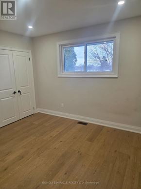 Oshawa (Donevan) apartment for rent - A room with a wooden floor and a window showing trees outside.