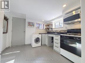 Toronto (Greenwood-Coxwell) apartment for rent - A white kitchen with a washing machine and a fridge.