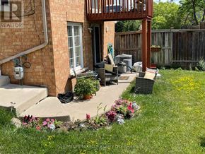 Mississauga (Central Erin Mills) duplex for rent - A small patio with a table and chairs is surrounded by a wooden fence and a grassy area with flowers.