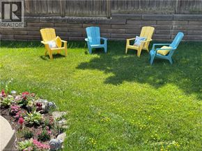 Mississauga apartment for rent - Four adirondack chairs are arranged in a row on a lawn.