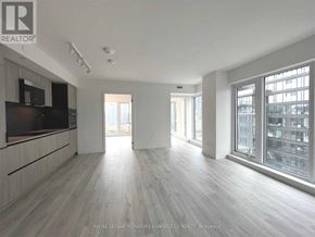 Toronto (Waterfront Communities) condo for rent - A spacious room with wooden flooring and large windows.