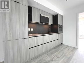 Toronto (Waterfront Communities) condo for rent - A modern kitchen with wooden cabinets and a black countertop.