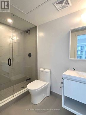 Toronto (Waterfront Communities) condo for rent - A white toilet sits next to a walk-in shower in a bathroom.