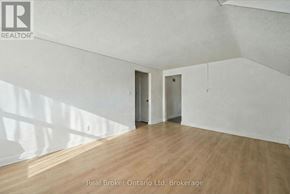 Kitchener multi-family for rent - A room with wooden flooring and white walls, with a Real Broker Ontario Ltd logo in the top left corner.