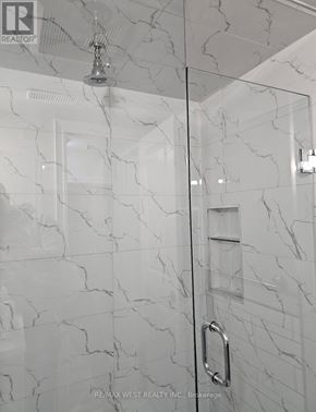 Toronto (Mimico) apartment for rent - A white marble bathroom with a glass shower door.