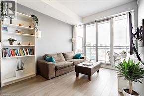 Kitchener condo for rent - A living room with a couch, a coffee table, a bookshelf, and a plant.