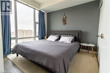 Kitchener condo for rent - A bedroom with a large bed and a view of the city.
