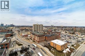 Kitchener condo for rent - A cityscape with a large building in the center and cars on the road.