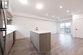 Barrie condo for rent - A spacious kitchen with wooden floors and white walls.