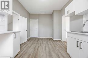 Wallaceburg apartment for rent - A white kitchen with wood flooring and a realtor logo.