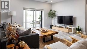 Windsor condo for rent - A living room with a grey couch, a wooden coffee table, a flat screen TV, and a plant.