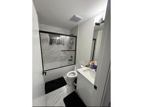 Surrey apartment for rent - A bathroom with a toilet, sink, and mirror.