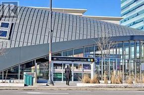 Vaughan (Vaughan Corporate Centre) condo for rent - A modern building with a glass facade and a person walking in front.