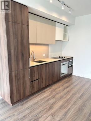 Vaughan (Vaughan Corporate Centre) condo for rent - A modern kitchen with wooden cabinets and a white wall.