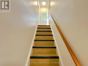 St. Catharines (Glendale/Glenridge) apartment for rent - A staircase with wooden steps and a white wall.