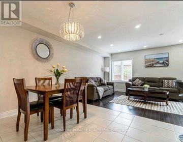 Hamilton (Stoney Creek) townhouse for rent - A well-lit living room with a dining table and a couch.